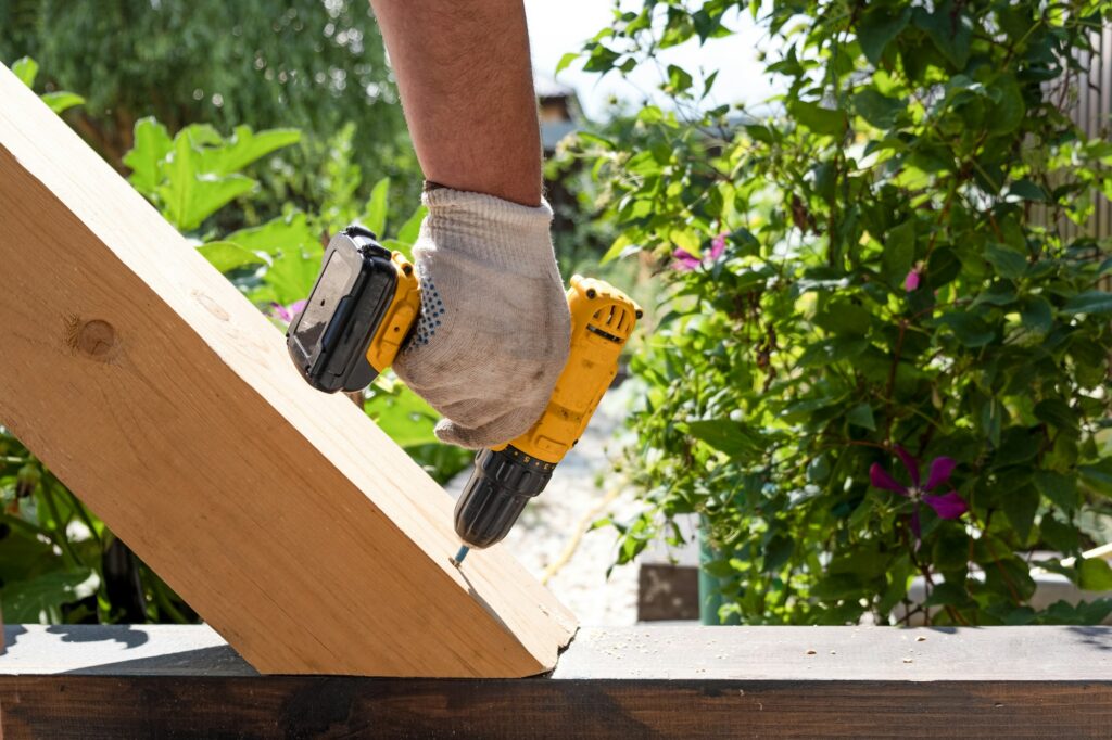 Screw driver in men hands. Repair wood construction. Cottage core