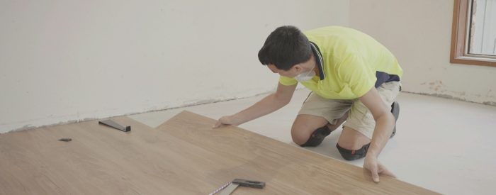 Man installing new timber laminated wooden floor, home improvement, house renovation project concept